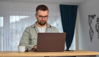 A young man using a laptop while working at home. photo
