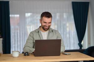 A happy man using a laptop while working at home office. photo
