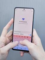 Travnik, Bosnia and Herzegovina, 02.08.2025. Close up of Asian female hands using DeepSeek app chat on phone to solve a reasoning problem on an isolated background, real photo. photo