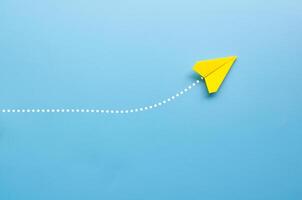 Top view of origami yellow paper airplane on blue background photo