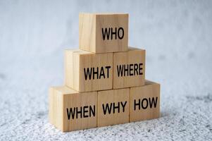 Side view of Who, What, Where, When, Why and How text on stacking wooden cubes. Fact finding concept photo