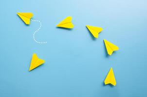 Top view of origami yellow paper airplane with one airplane leaving the group photo