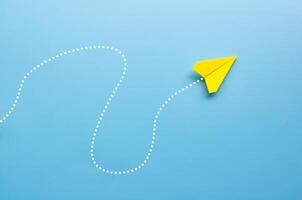 Top view of origami yellow paper airplane on blue background with customizable space for text photo