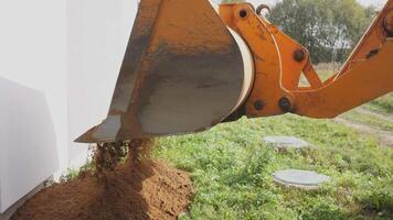An excavators bucket is currently dumping soil near a construction site, helping with the ongoing project video
