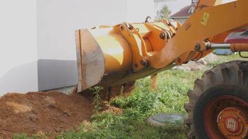 Excavation work is being carried out by a backhoe loader in close proximity to a foundation wall segment video