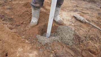 Installing a fence beam on a construction site. A worker carefully pouring concrete to form a strong foundation at a busy construction site for stability video