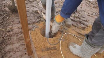 A dedicated worker is performing groundwork needed for the installation of structural support in muddy conditions video