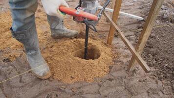 A dedicated worker using a powerful auger tool to dig a deep hole, showcasing outdoor construction work video