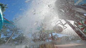 água cascatas a partir de uma ampla balde às uma vibrante água parque, criando salpicos e excitação para visitantes desfrutando verão Diversão video