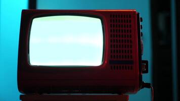 Old red television set displaying static white noise on blue background video