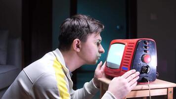 a man stares at the screen of an old vintage tube TV with white noise video
