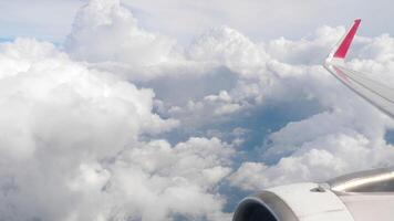 View of airplane wings in clouds through porthole. Blue sky background. Beautiful clouds and airplane wings from the window with beautiful blue sky video