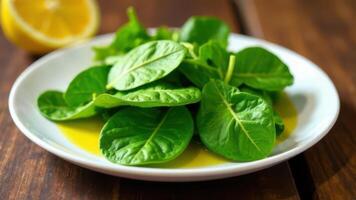 Fresh baby spinach leaves with lemon dressing on white plate photo