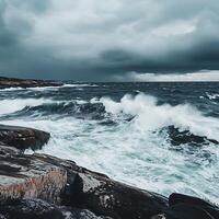 A person standing on a rocky shoreline with a large wave crashing in the background photo