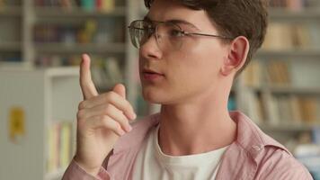 Portrait in school library college thinking hesitate pondering difficult decision problem solution Caucasian student boy looking for answer counting with fingers one two man male guy education think video