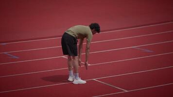An athlete is seen recovering on the track after completing an intense and challenging sprint video