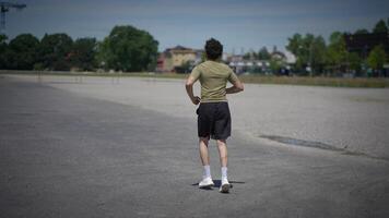 A person is seen jogging energetically along an empty track beneath a clear blue sky video