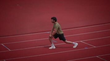 An athlete is stretching on a track field to prepare themselves effectively before a race video