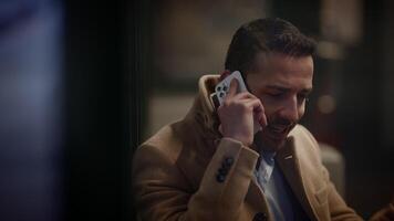 A man wearing a coat is engaged in a phone conversation while situated in an urban environment video