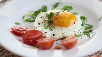 Fried eggs with greens and tomatoes on a white plate video