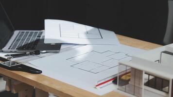 A laptop, a blueprint and a model of a house on a table video