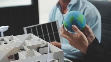 A man holding a globe in front of a model of a house video