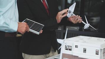 Two men in suits are looking at a model of a house video