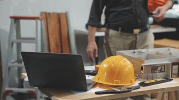 A man in a hard hat and a laptop on a table video
