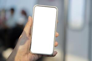 Mockup image of hand holding white mobile phone with blank screen in subway photo