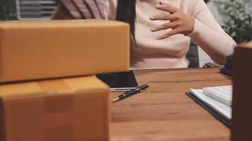 A woman is sitting at a desk with boxes and a laptop video