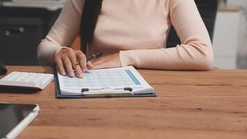 A woman is sitting at a desk with a notebook and a calculator video