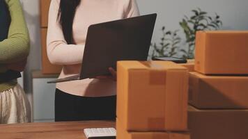 Two people standing in front of boxes with a laptop video