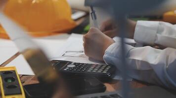 A person is working on a project with a calculator and a hard hat video