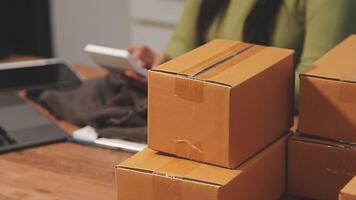 A woman is sitting at a table with a laptop and a stack of boxes video