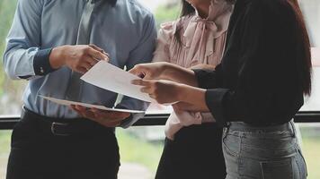Three business people standing around a table with papers video