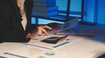 A woman in a business suit is using a calculator and papers video