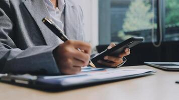 A business person is using a smartphone and pen to write on a piece of paper video