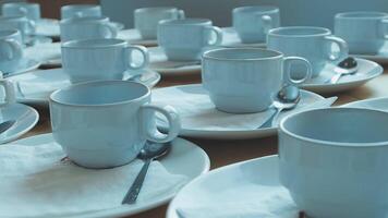 Many white coffee cups and saucers are arranged on a table video