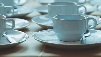 Many white coffee cups and saucers sit on a table video