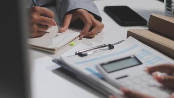 en företag person är skrivning på en anteckningsbok medan annan person är använder sig av en kalkylator video