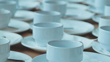 Many white coffee cups and saucers are arranged on a table video