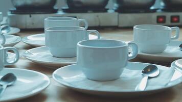 Many white coffee cups and saucers are on a table video