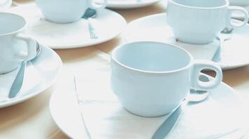 Many white coffee cups and saucers on a table video