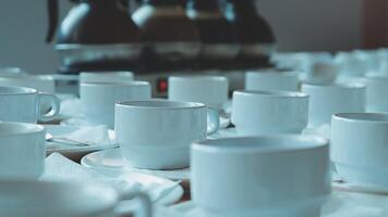 Many white coffee cups and saucers are arranged on a table video