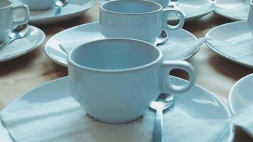 Many white coffee cups and saucers on a table video
