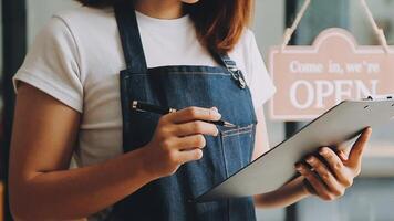 A woman in an apron is holding a clipboard and writing on it video