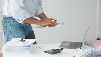A man is standing in front of a laptop and a stack of papers video