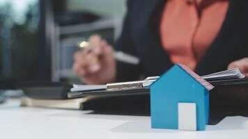 A woman in a business suit is working on a house model video