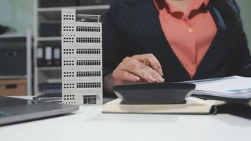 A woman is using a calculator to calculate the cost of a building video