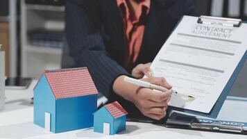 A woman signing a contract with a house model video